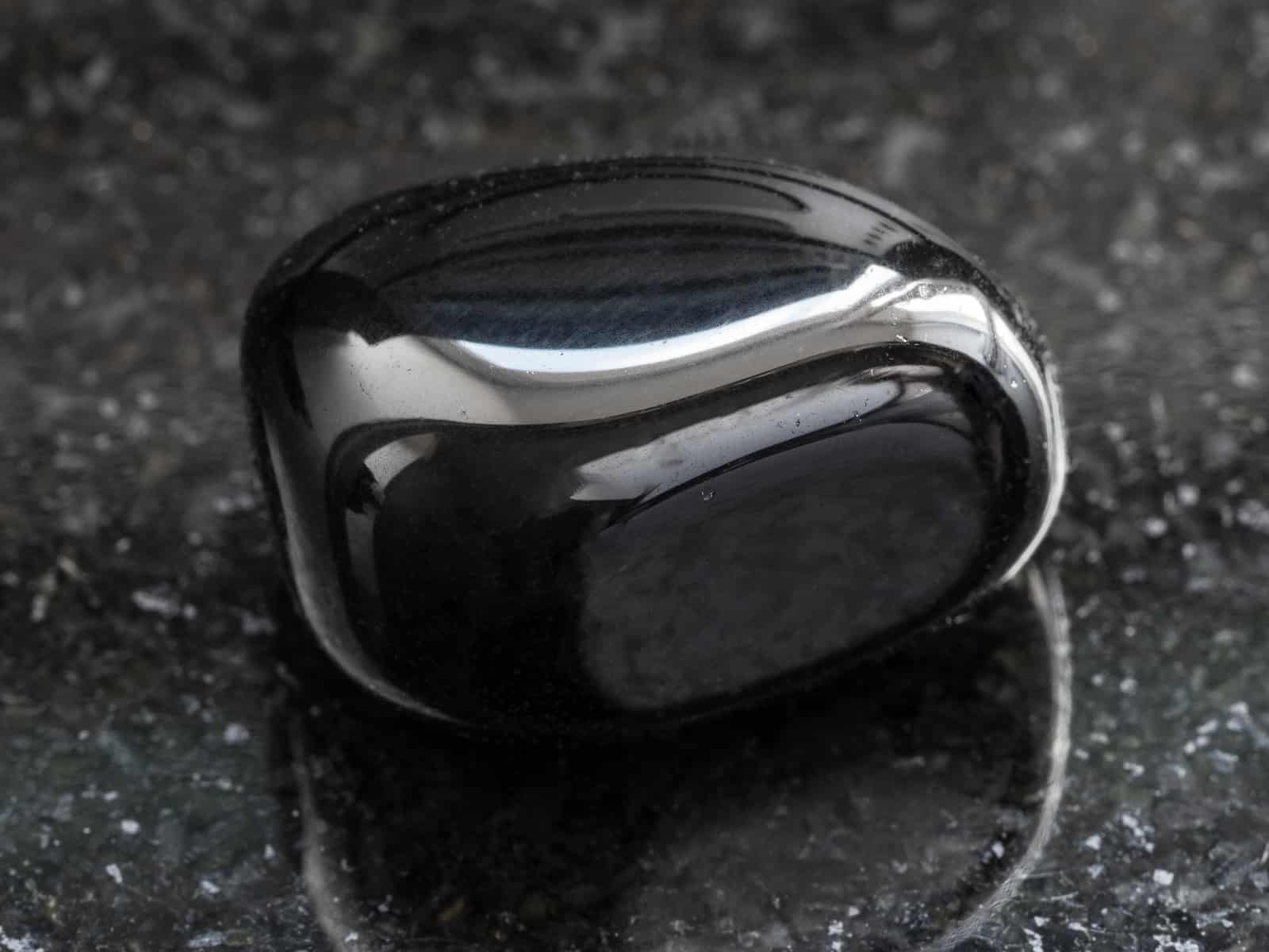 polished black Onyx gemstone on dark granite background