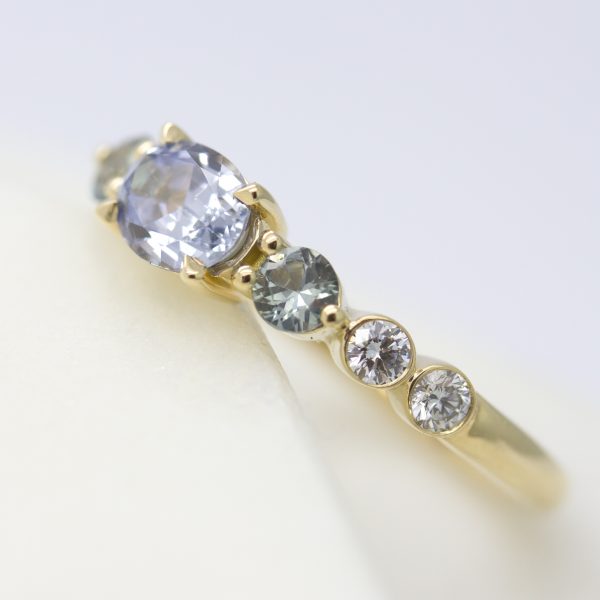 Blue sapphire engagement ring with bezel set round diamonds set in yellow gold