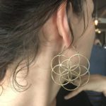 Girl wearing flower of life symbol earrings