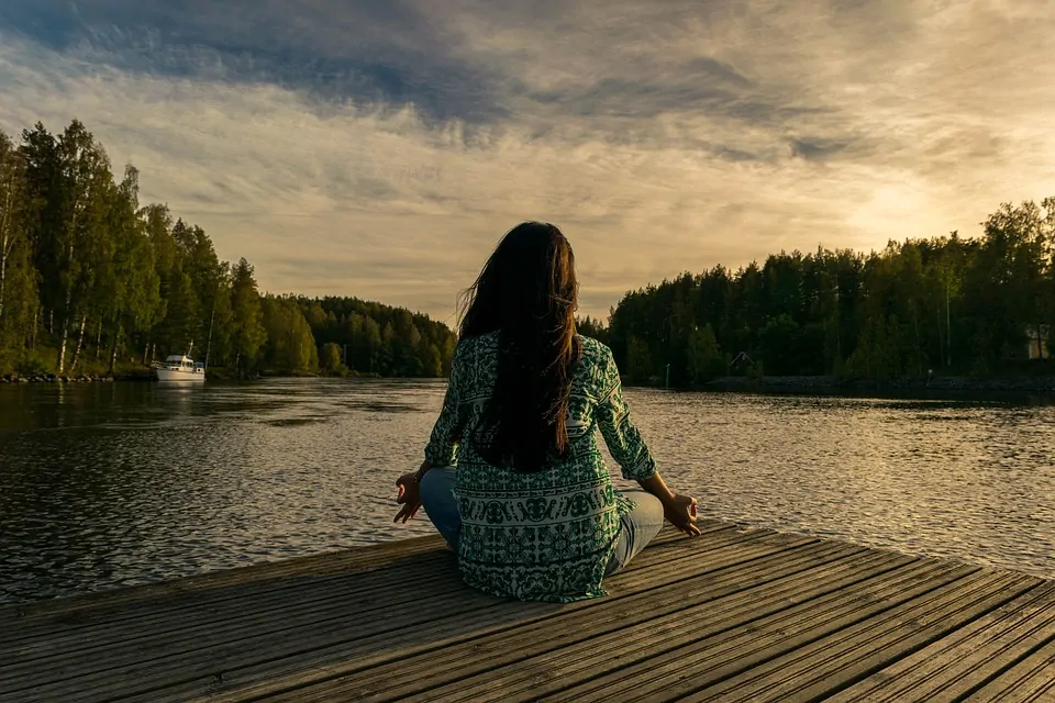 Girl sitting and meditating in front of river