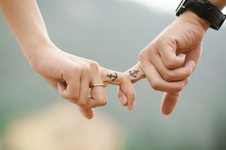 Couple holding fingers with anchor tattoo