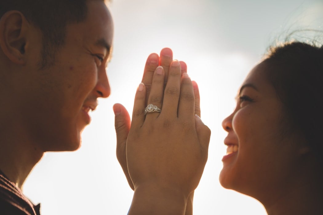 Girl wearing halo engagement ring holding boy's hand