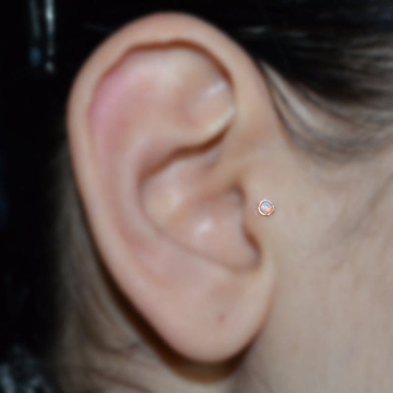 Opal tragus stud on girl's ear