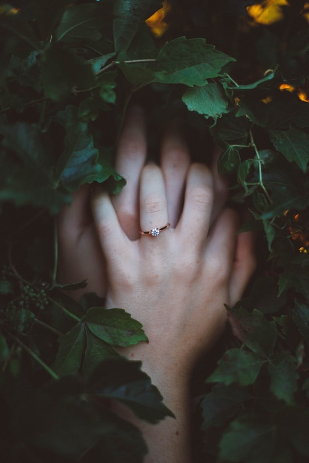 Girl's hand wearing dainty engagement ring
