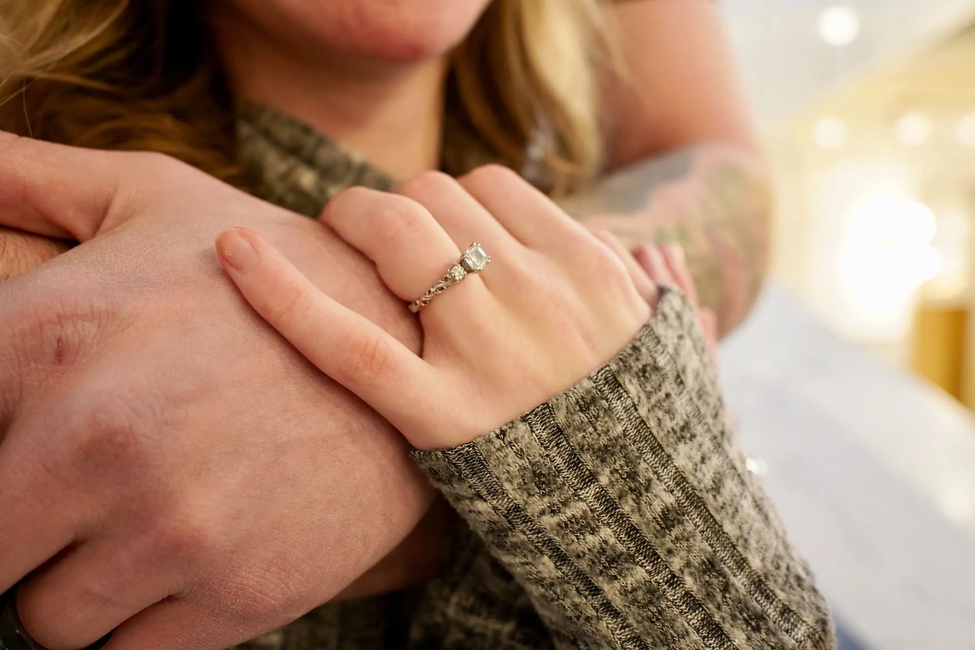 couple holding hands with engagement ring