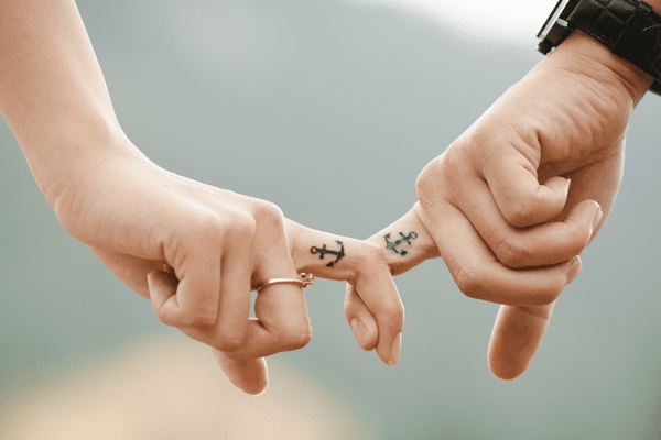 two hands with anchor tattoos on fingers