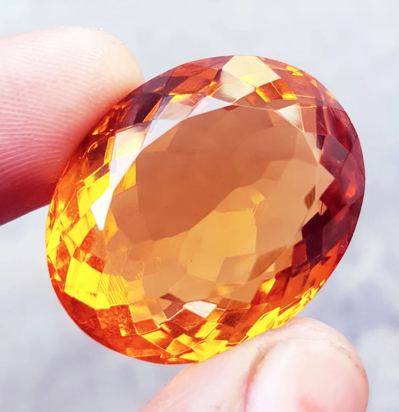 holding an orange topaz gemstone