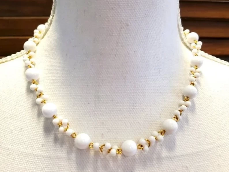 designer signed trifari white beaded necklace on a neck manequin