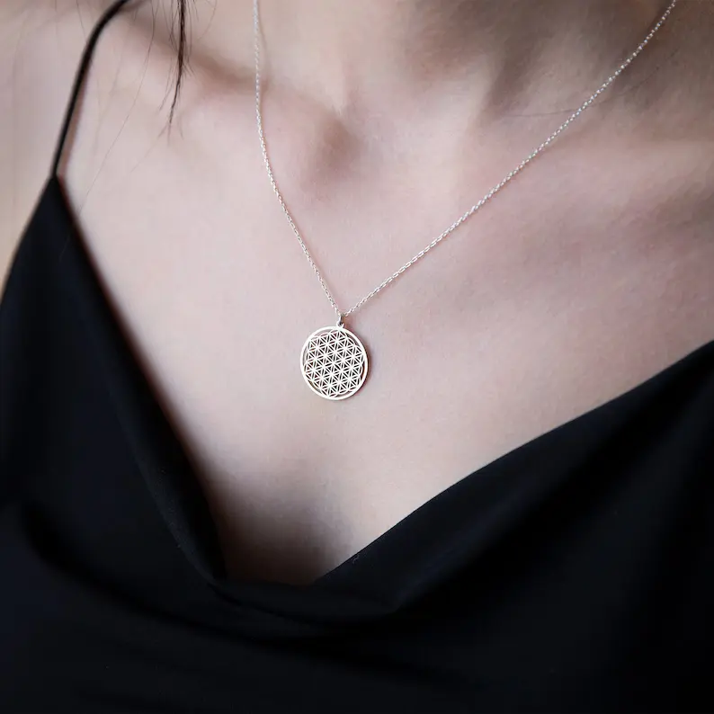 a woman wearing a flower of life necklace