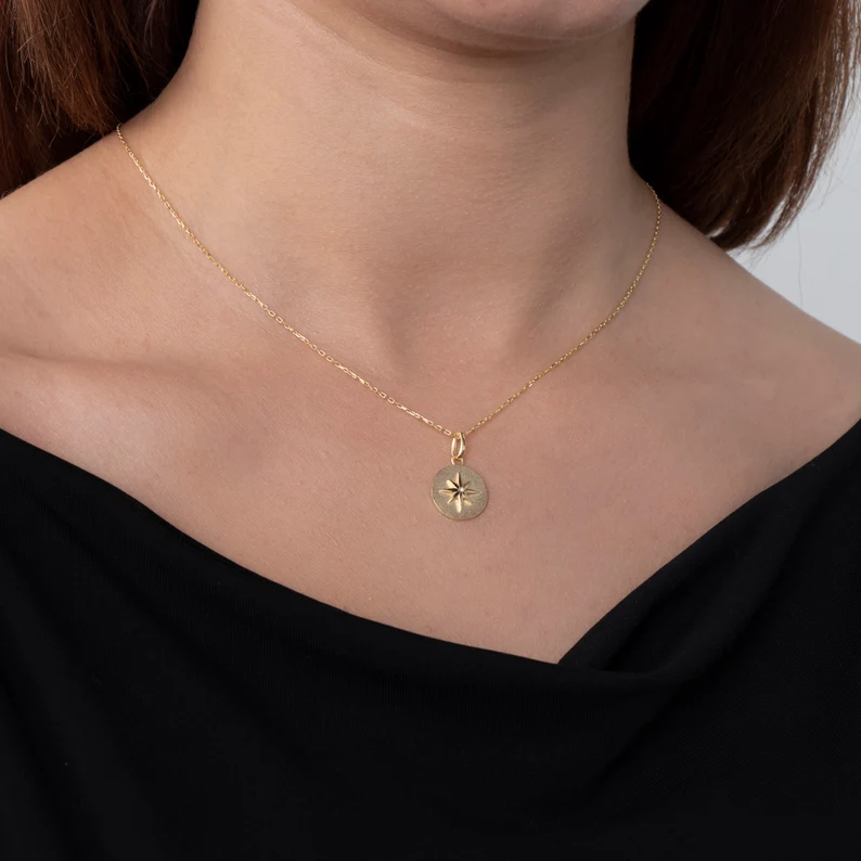 a woman wearing a gold starburst design necklace