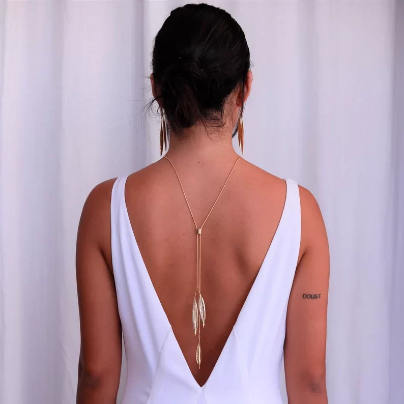 a woman in white dress with a minimalist bridal backdrop necklace
