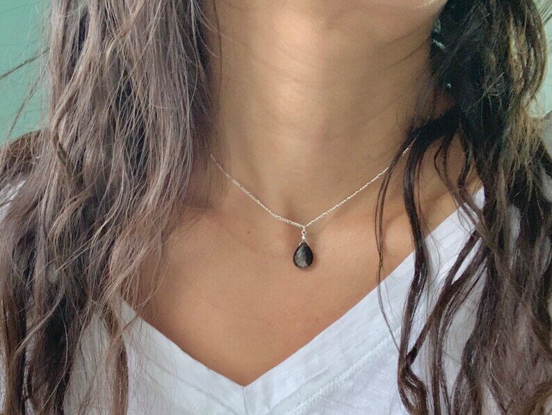 a woman wearing a black moonstone necklace