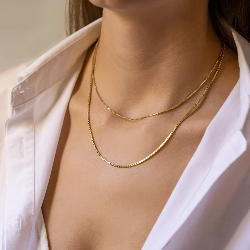 a woman wearing box chain layered necklaces