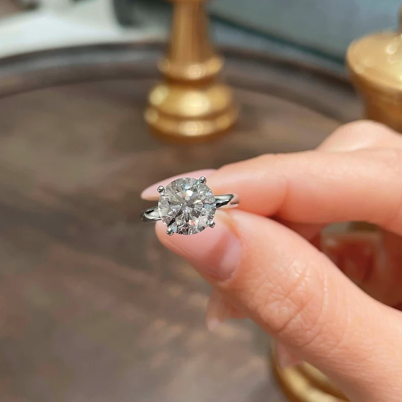 holding a solitaire diamond engagement ring