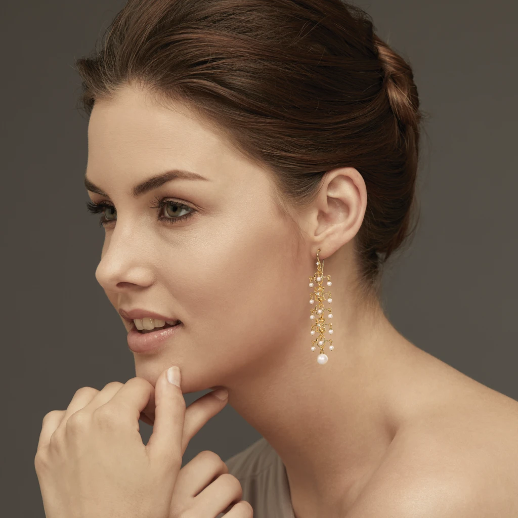 a woman wearing pearl drop earrings