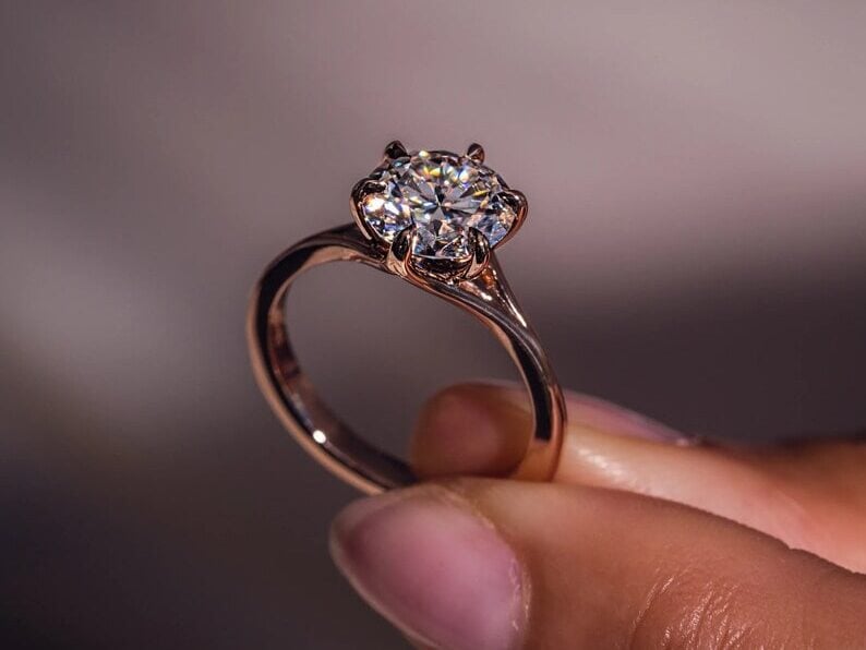 2 carat solitaire diamond ring in between fingers