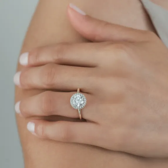 a hand with halo diamond ring