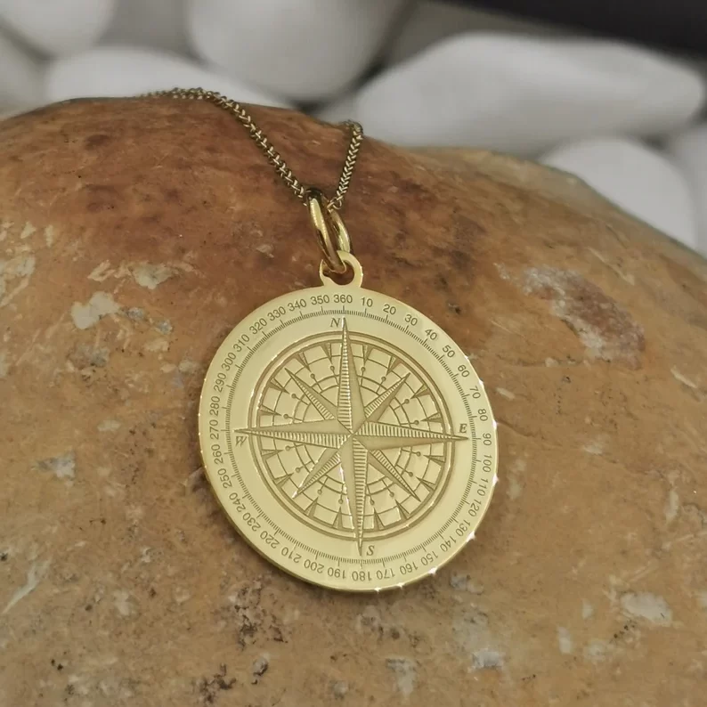 solid gold compass necklace on top of a stone