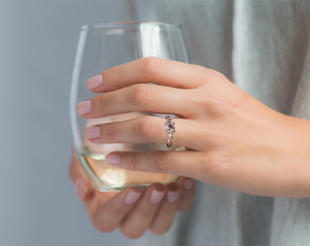 a hand with engagement ring holding a glass