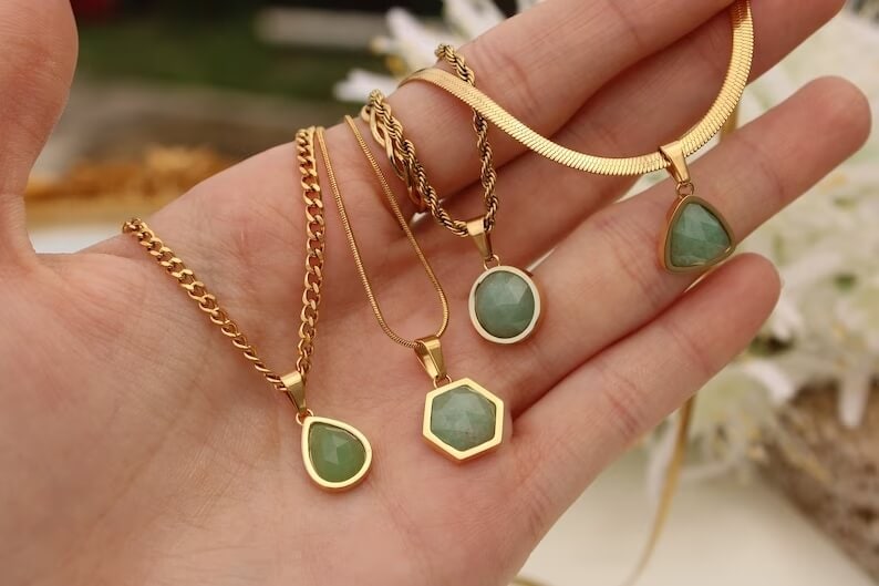 green aventurine pendant necklaces on a hand