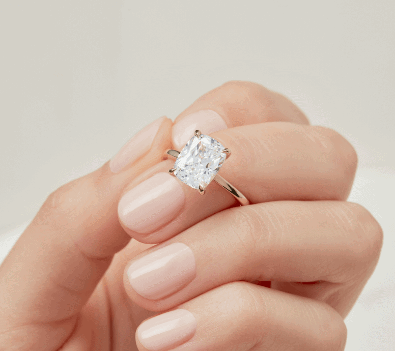 cushion cut solitaire engagement ring in between fingers