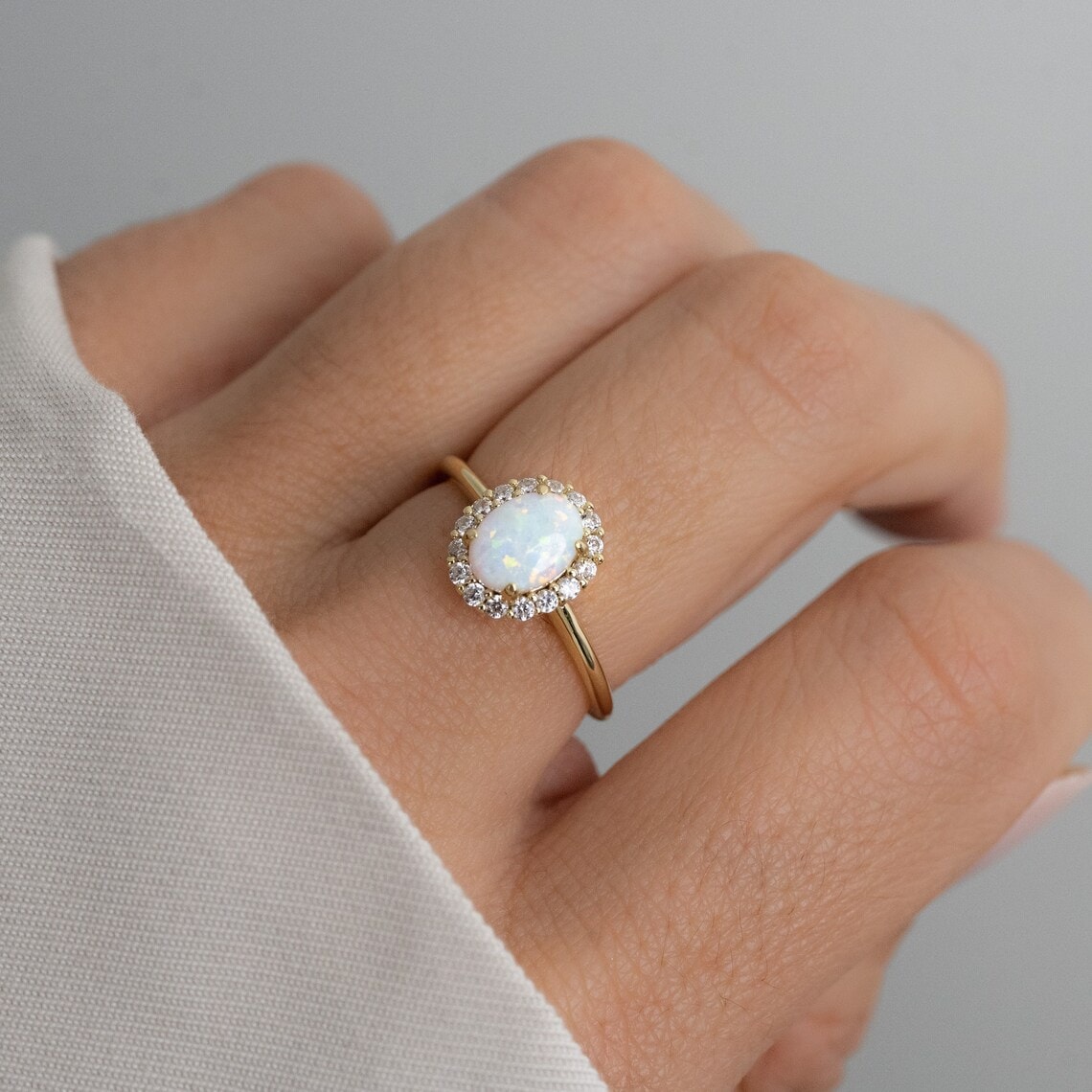 dainty opal ring on the middle finger