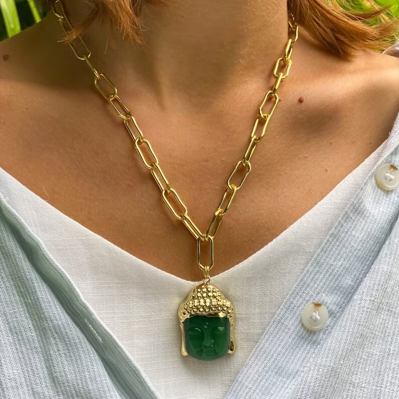 green jade buddha necklace on the woman's neck