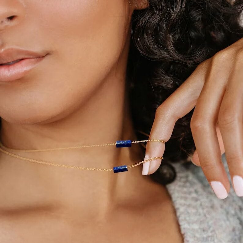 a woman holding lapis lazuli necklace on her neck