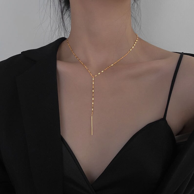a woman wearing a gold minimalist lariat necklace