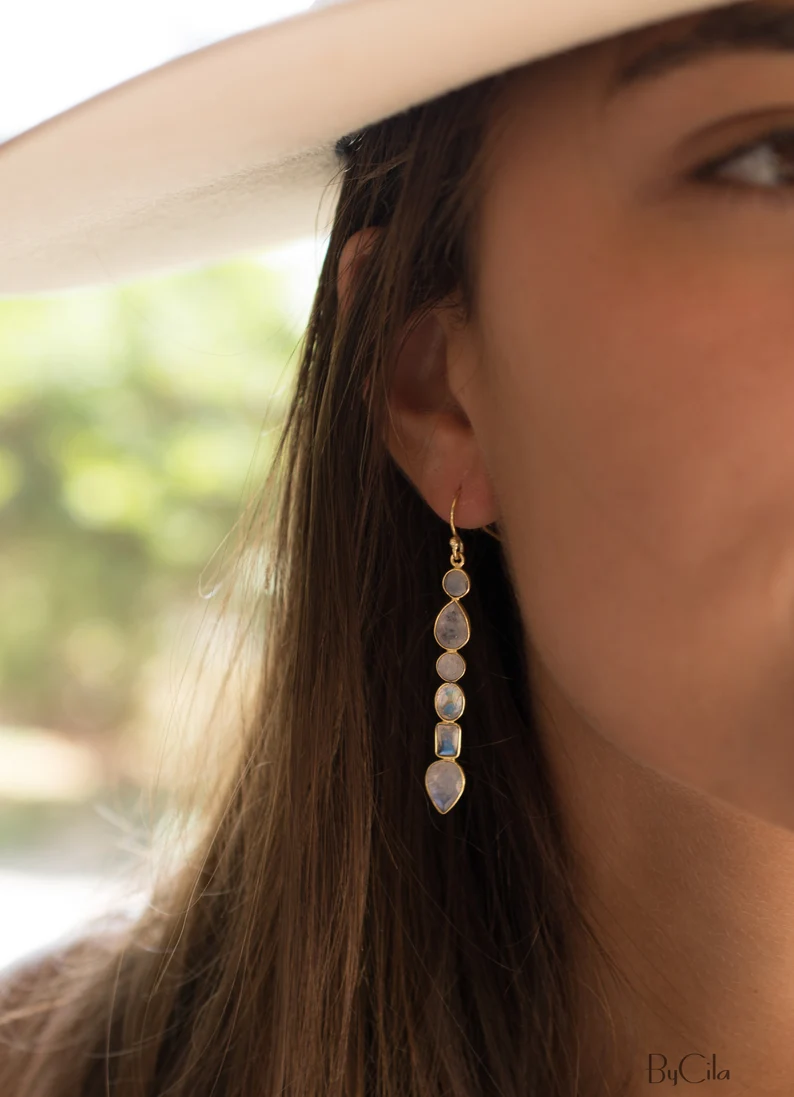 moonstone gold long earring on the woman's ear