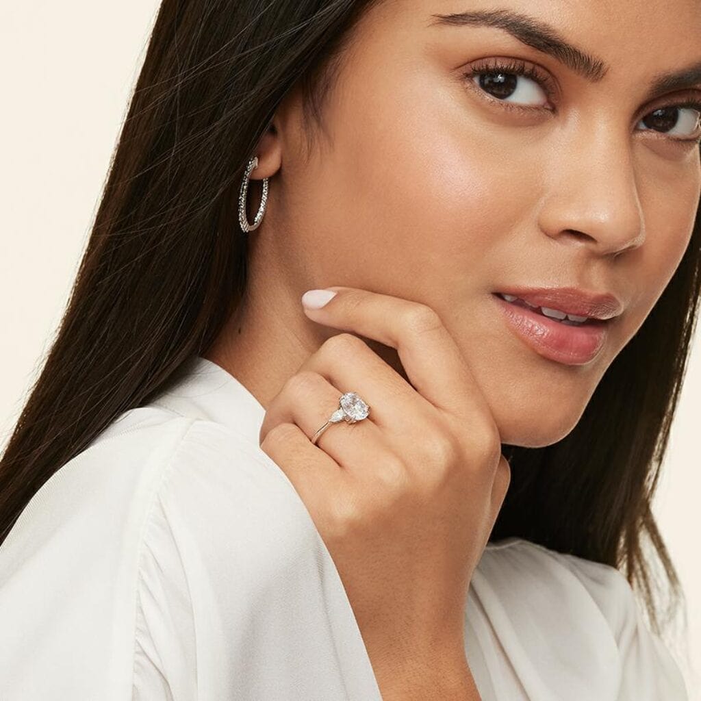 a woman wearing a three-stone diamond engagement ring