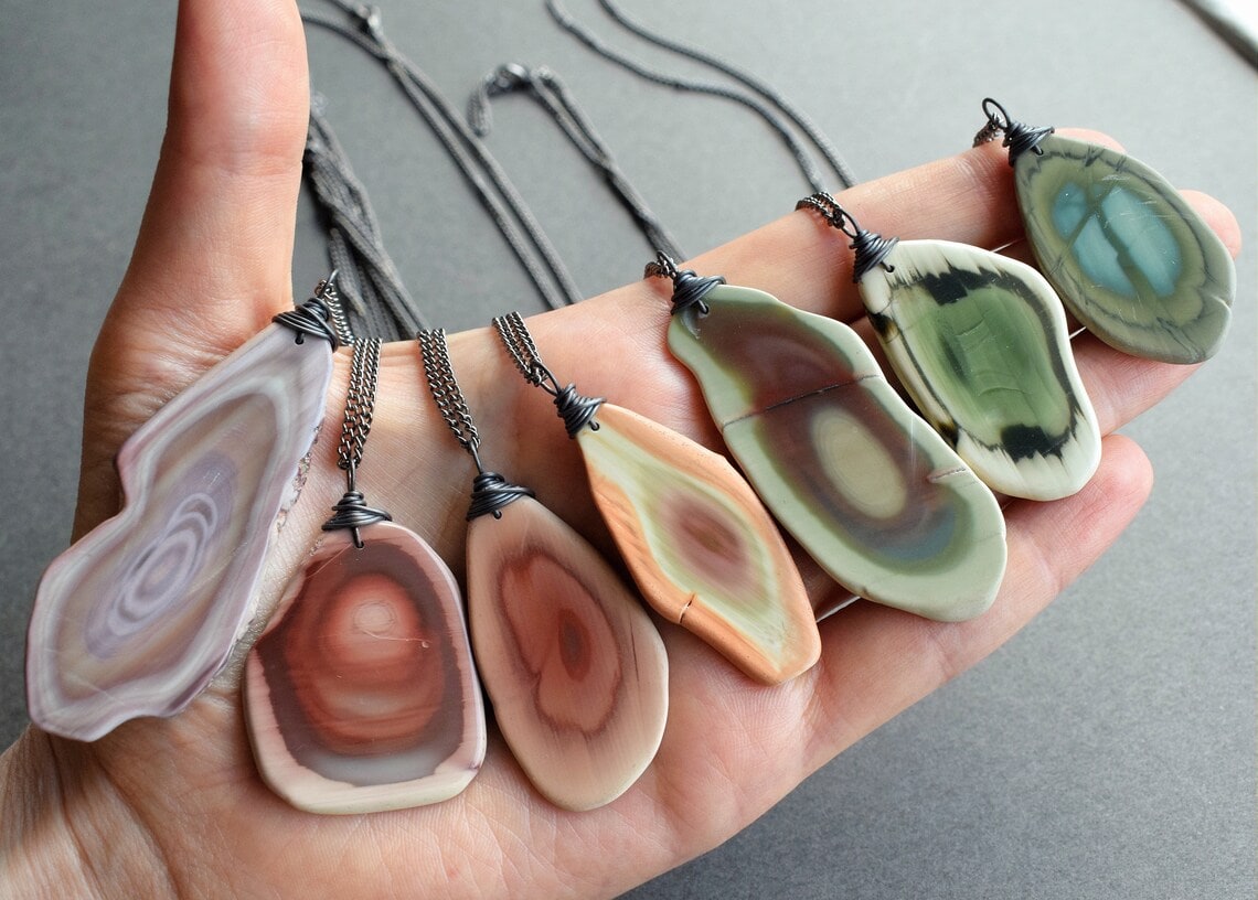 a hand holding raw imperial jasper necklaces