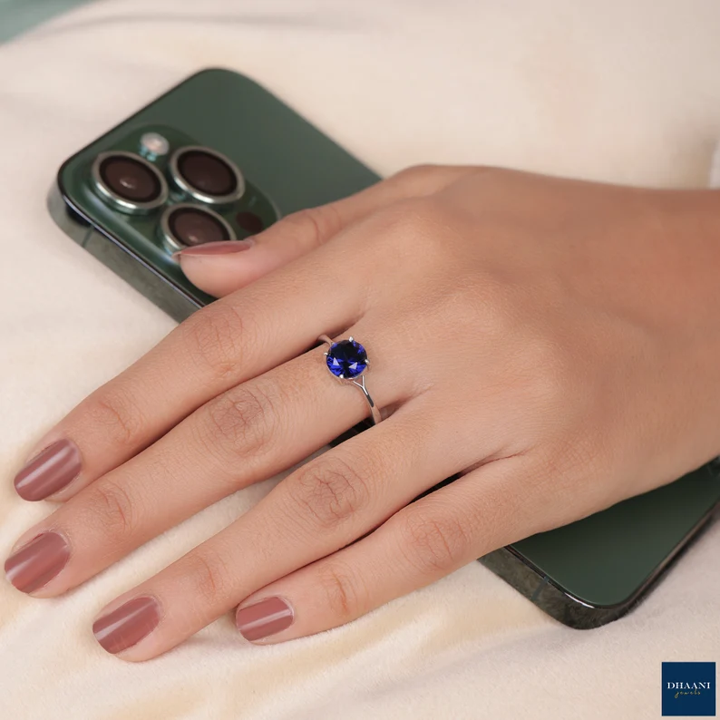 a woman's hand wearing a silver sapphire ring