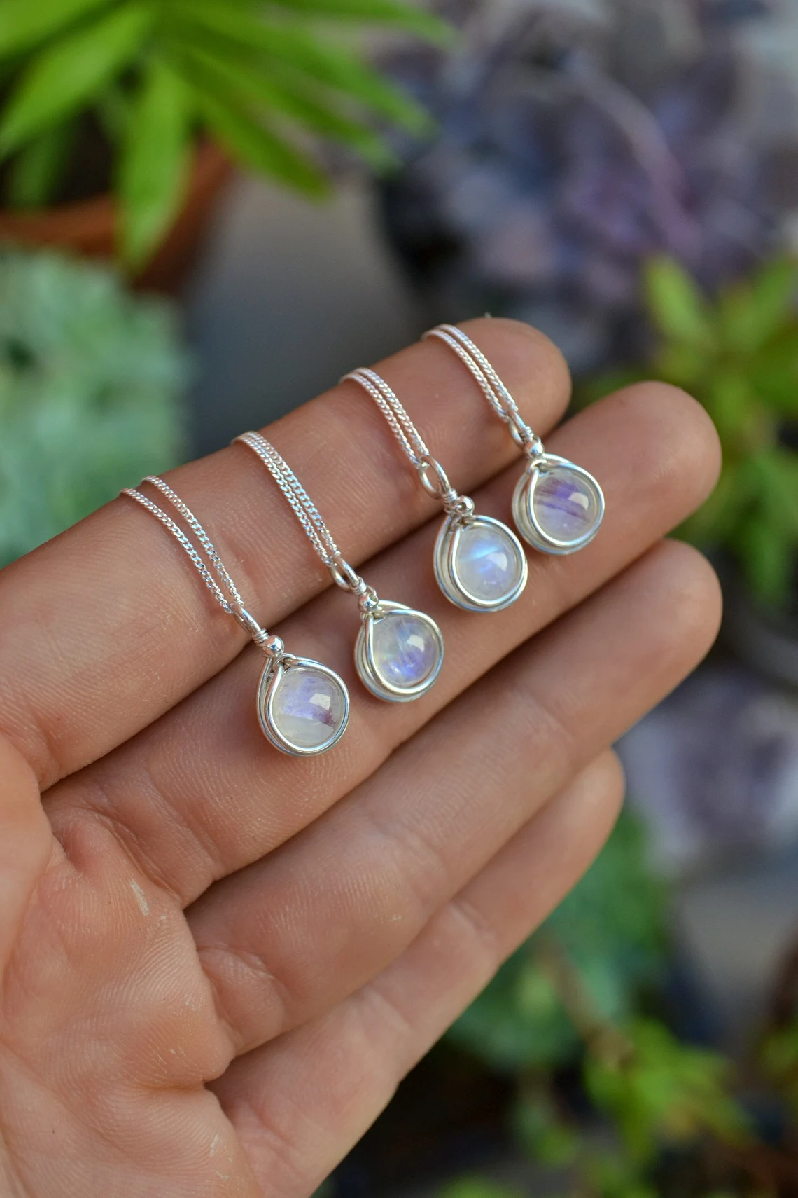 a hand with sterling silver moonstone pendant necklaces
