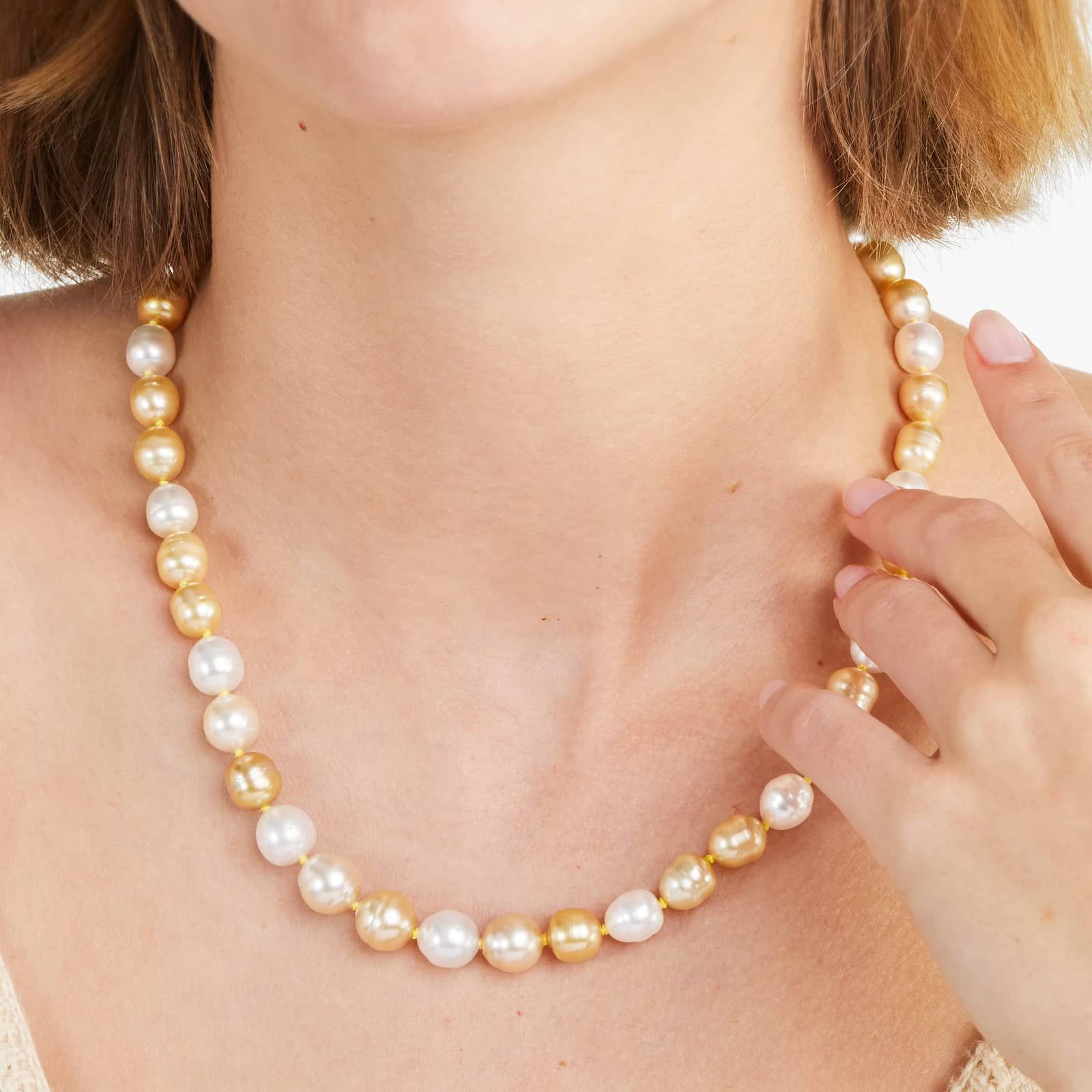 a woman wearing white and golden south sea pearl strand