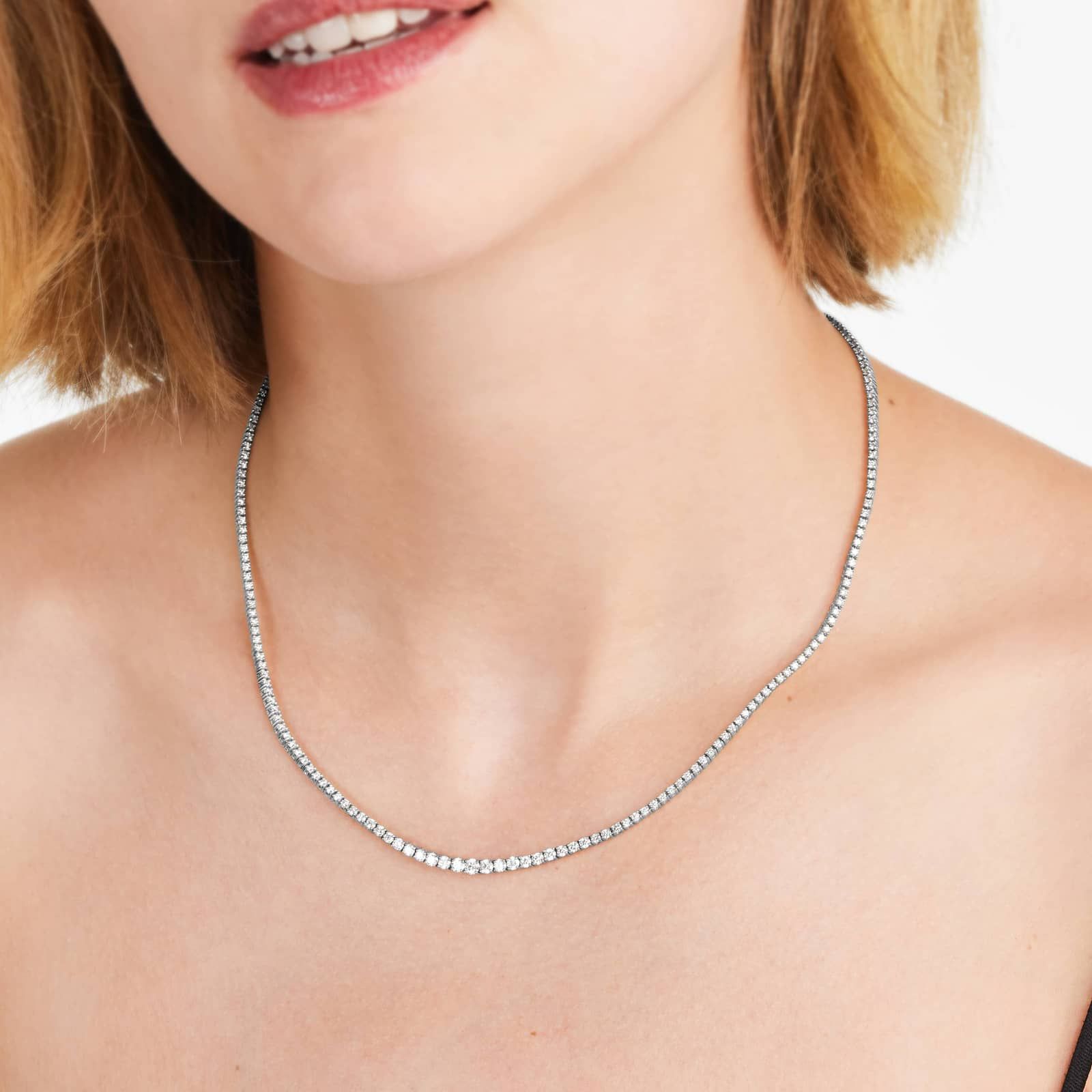 a white gold riviera tennis necklace on the woman's neck