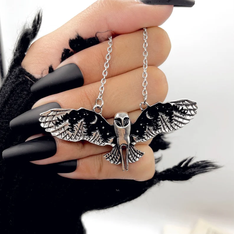 a hand holding black owl pendant necklace