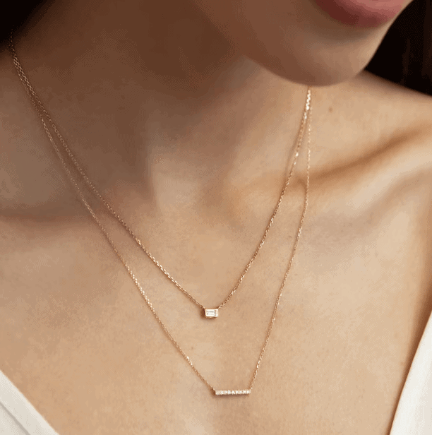 petite pave bar necklace and baguette diamond necklace on woman's neck