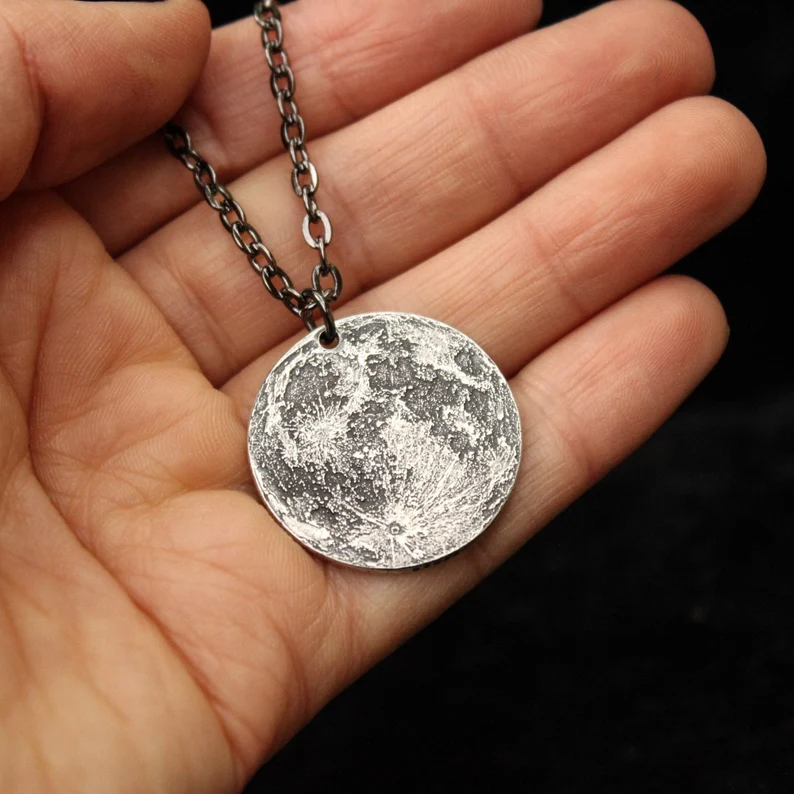 silver full moon necklace on a hand