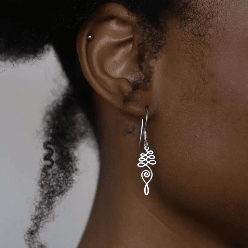 silver unalome earring on woman's ear