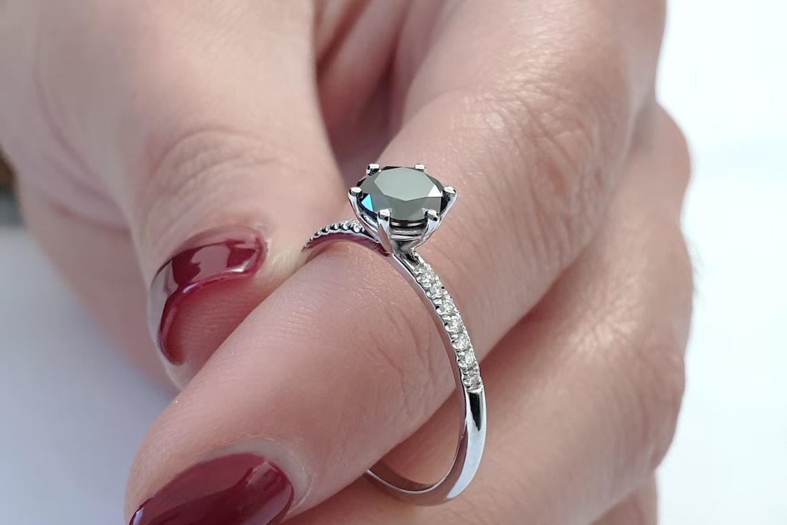 a hand holding black diamond engagement ring