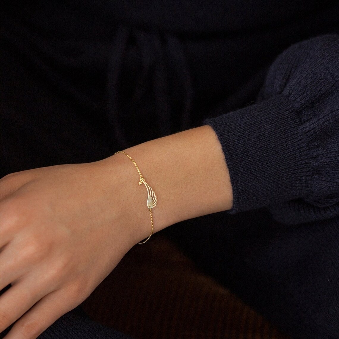 gold angel wing bracelet on the wrist