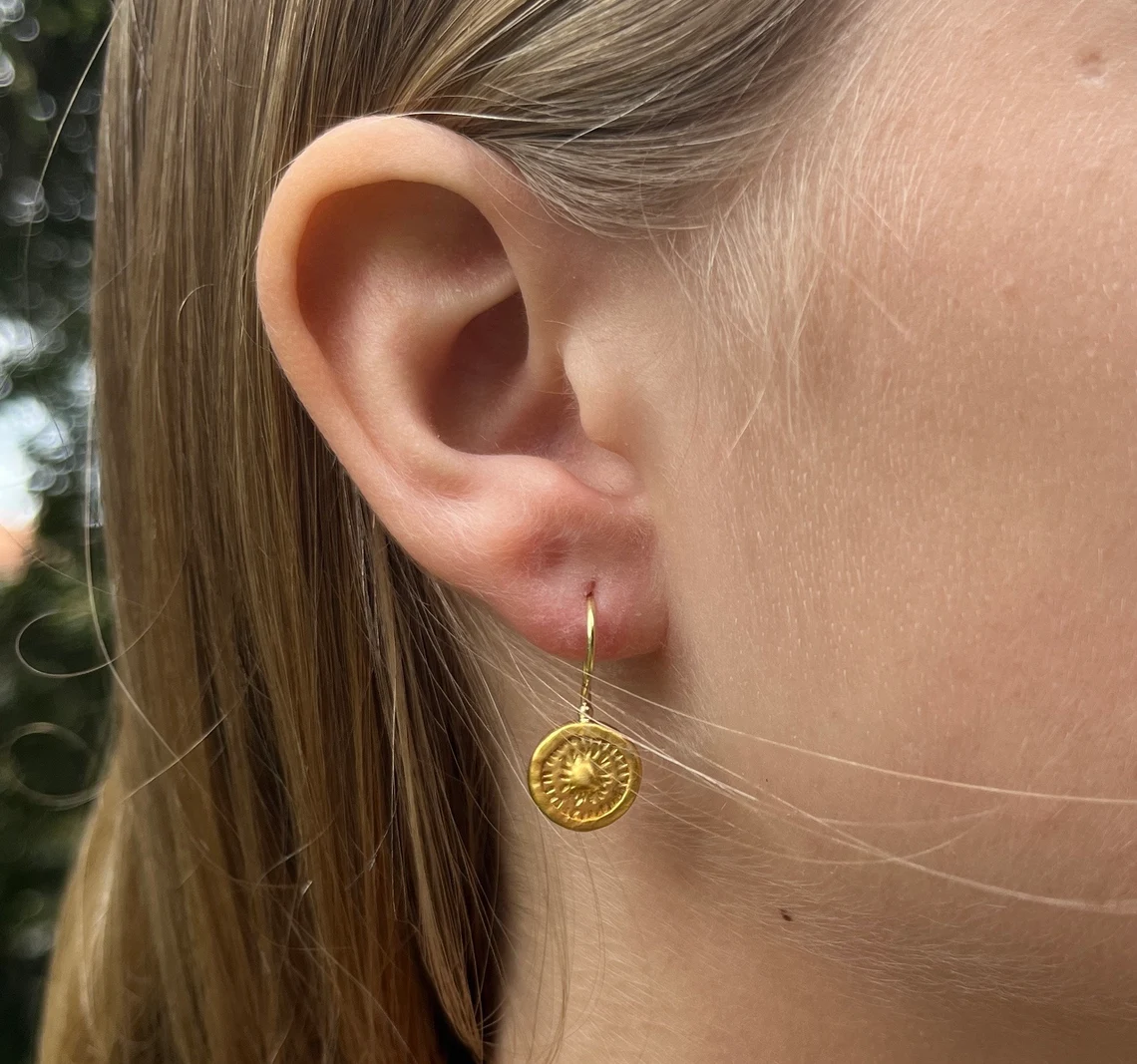 24k solid gold earring on the woman's ear