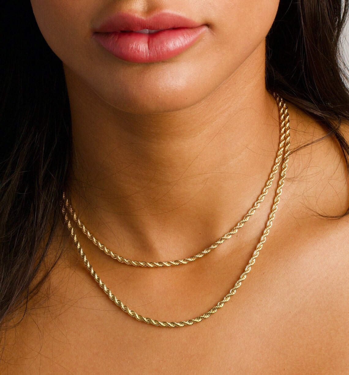 gold rope chain necklaces on the woman's neck