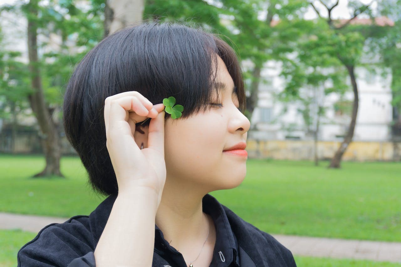 Woman Holding Green Leaf on Her Ear