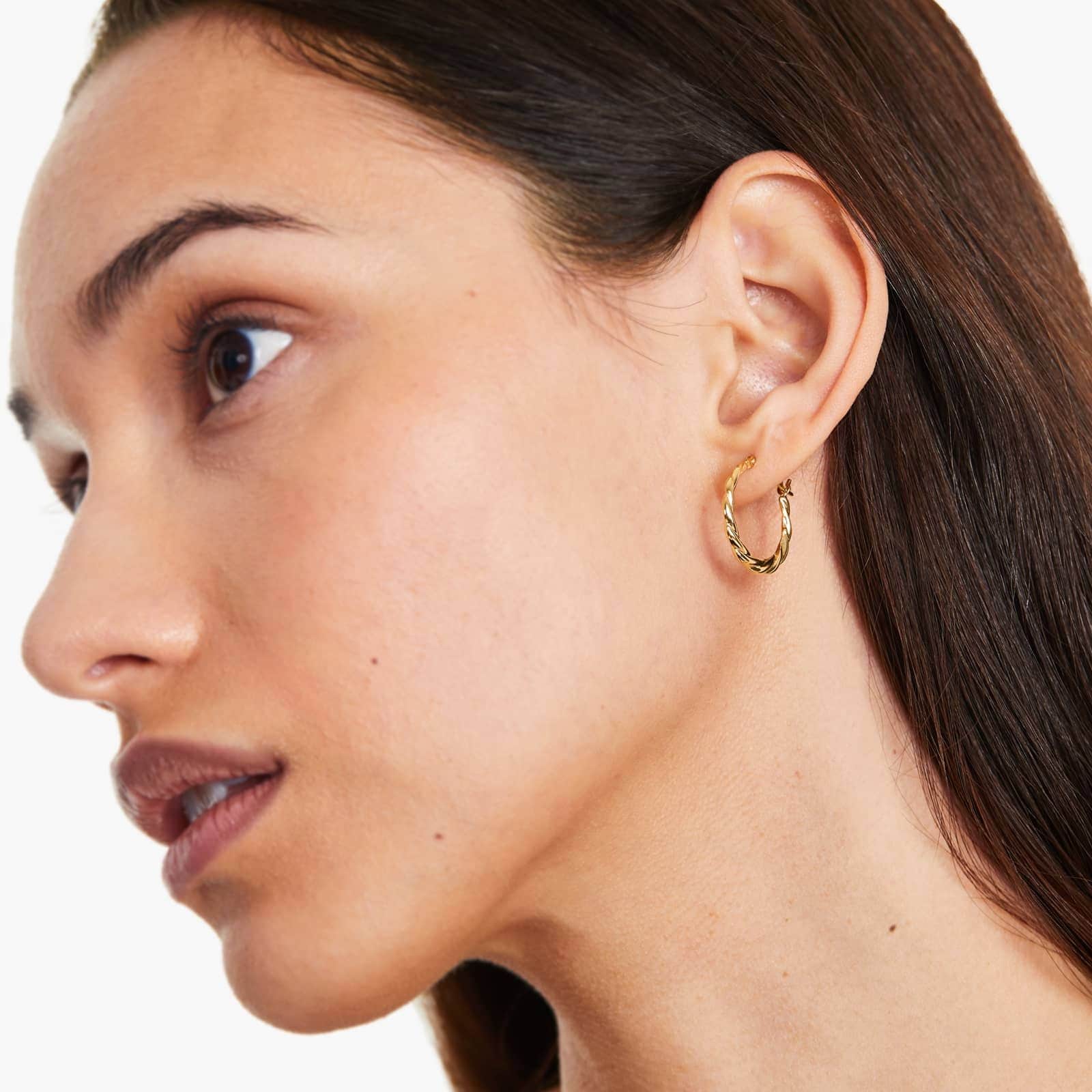 gold woven hoop earring on the woman's ear