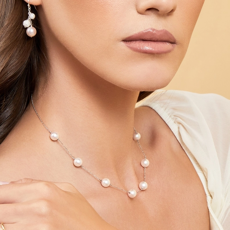 a woman wearing japanese akoya pearl tincup necklace and earrings
