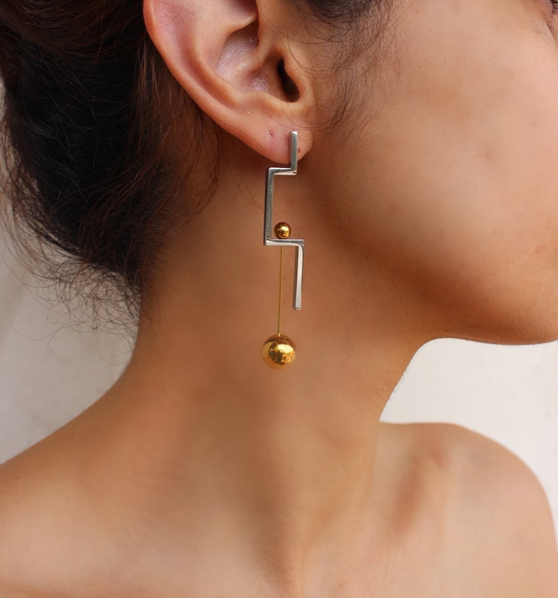 modern geometric steel earring on the woman's ear