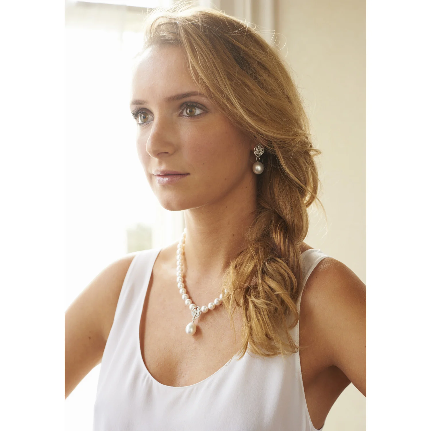 a woman wearing white south sea pearl diamond earrings and necklace