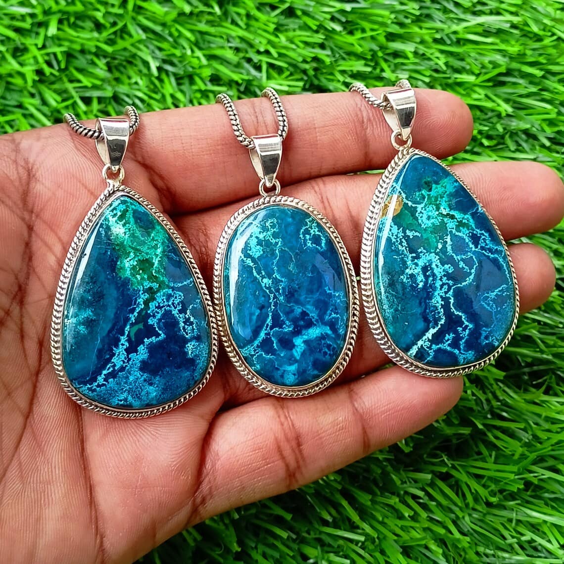 a hand holding azurite pendant necklaces